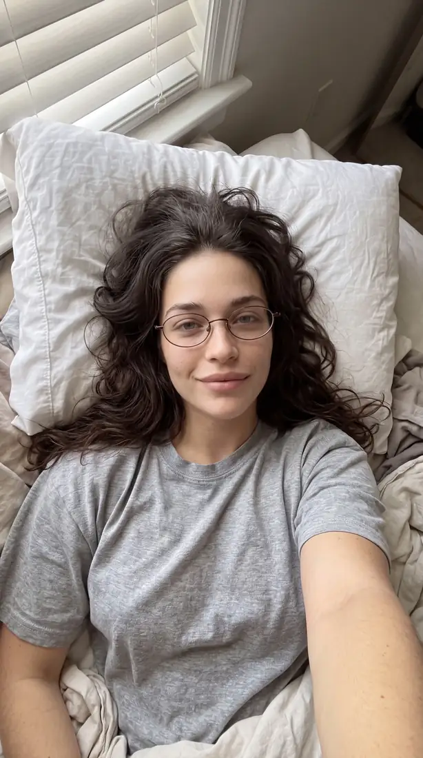 Égoportrait en plongée au lit, lunettes ovales